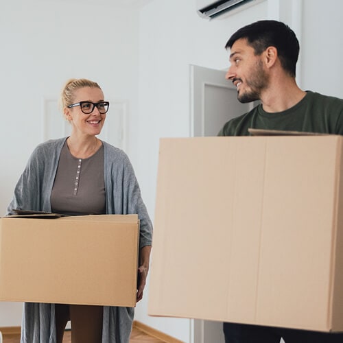 A couple moving boxes into their new apartment.
