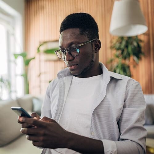 Someone looking at their phone with a surprised look, wondering what to do if a scammer has their phone number.